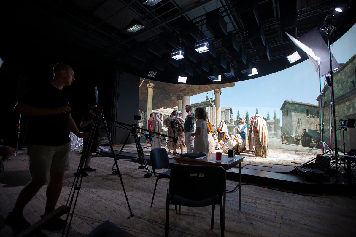On set: actors in period costume in front of an ancient city on the LED wall
